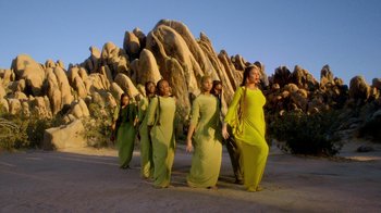 Movie still from “Black Is King” (2020), directed by Julian Klincewicz – A group of people in green dresses standing in front of a rock formation; Extreme Wide shot, High angle