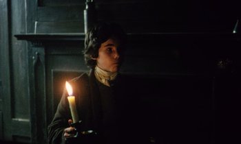 Movie still from “Black Jack” (1979), directed by Ken Loach – A young man holding a lit candle in a dark room; Medium shot, High angle