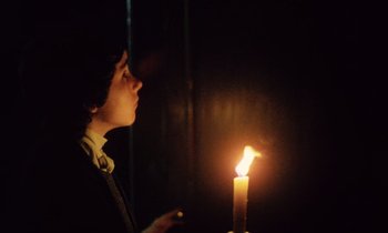 Movie still from “Black Jack” (1979), directed by Ken Loach – A person holding a lit candle in a dark room; Medium shot, Low angle