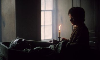 Movie still from “Black Jack” (1979), directed by Ken Loach – A person sitting in a bed with a lit candle; Medium shot, Over the shoulder angle