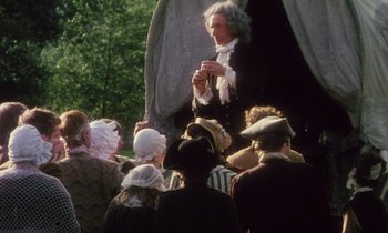 Movie still from “Black Jack” (1979), directed by Ken Loach – An old man is holding a glass of wine while a group of people are watching him; Medium shot, High angle