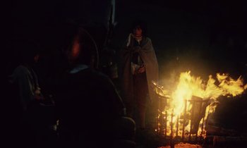 Movie still from “Black Jack” (1979), directed by Ken Loach – A person standing next to a fire at night; Wide shot, High angle