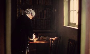 Movie still from “Black Jack” (1979), directed by Ken Loach – An old woman standing at a table in front of books; Medium shot, High angle