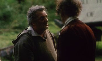 Movie still from “Black Jack” (1979), directed by Ken Loach – Two men talking to each other in a wooded area; Medium shot, Over the shoulder angle
