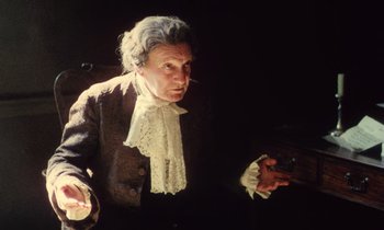 Movie still from “Black Jack” (1979), directed by Ken Loach – An older man wearing a wig and a lace shirt; Medium shot, High angle