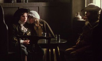 Movie still from “Black Jack” (1979), directed by Ken Loach – Two women sitting at a table in front of a man; Medium shot, Over the shoulder angle