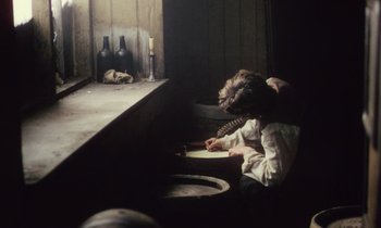 Movie still from “Black Jack” (1979), directed by Ken Loach – A person sitting in a room writing on a paper; Medium shot, High angle