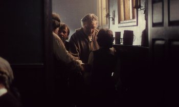Movie still from “Black Jack” (1979), directed by Ken Loach – A group of people standing around a table; Medium shot, Over the shoulder angle