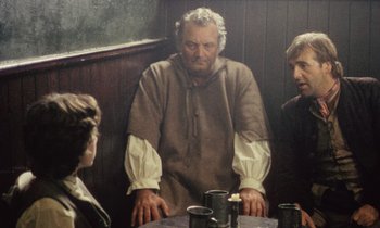 Movie still from “Black Jack” (1979), directed by Ken Loach – A painting of a man in medieval garb sitting at a table with two other men; Medium shot, Over the shoulder angle