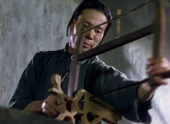 Movie still from “Black Narcissus” (1947), directed by Emeric Pressburger – A man is cutting wood with a pair of scissors; Medium shot, Low angle