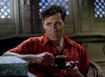Movie still from “Black Narcissus” (1947), directed by Emeric Pressburger – A man in a red shirt holding a cup of coffee; Close Up shot, Over the shoulder angle