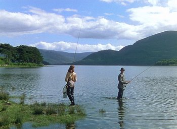 Movie still from “Black Narcissus” (1947), directed by Emeric Pressburger – A man and a woman fishing in a body of water; Wide shot, Low angle