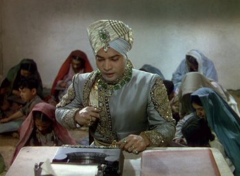 Movie still from “Black Narcissus” (1947), directed by Emeric Pressburger – A man wearing a turban is writing on a typewriter; Medium shot, High angle