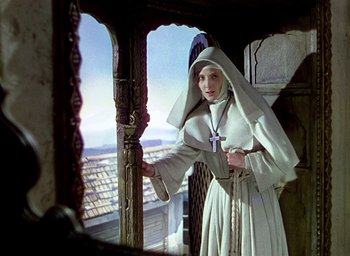 Movie still from “Black Narcissus” (1947), directed by Emeric Pressburger – A woman dressed as a nun standing in front of a window; Medium shot, Low angle