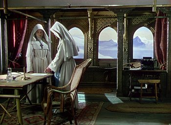 Movie still from “Black Narcissus” (1947), directed by Emeric Pressburger – Two women dressed as nuns are standing in front of a table; Wide shot, High angle