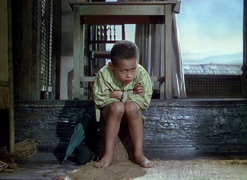 Movie still from “Black Narcissus” (1947), directed by Emeric Pressburger – A young boy sitting on the ground in front of a building; Medium shot, Low angle