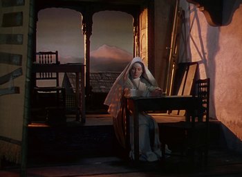 Movie still from “Black Narcissus” (1947), directed by Emeric Pressburger – A nun sitting at a table in front of an open window; Wide shot, High angle