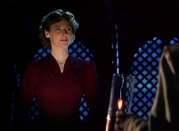 Movie still from “Black Narcissus” (1947), directed by Emeric Pressburger – A woman standing in front of a lit candle; Medium shot, Low angle