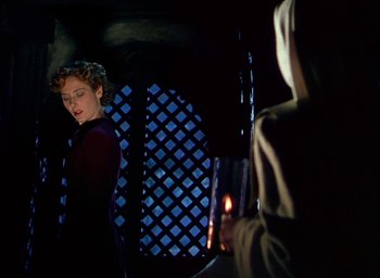 Movie still from “Black Narcissus” (1947), directed by Emeric Pressburger – A woman standing next to a person holding a candle; Medium shot, Low angle