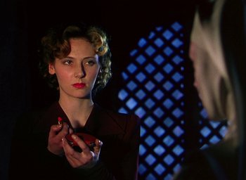 Movie still from “Black Narcissus” (1947), directed by Emeric Pressburger – A woman holding a cell phone in front of a mirror; Close Up shot, Over the shoulder angle