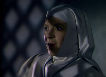 Movie still from “Black Narcissus” (1947), directed by Emeric Pressburger – A woman wearing a hood is looking at the camera; Close Up shot, Low angle