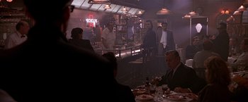 Movie still from “Black Rain” (1989), directed by Ridley Scott – A group of people sitting at a table in front of a bar; Wide shot, Over the shoulder angle