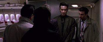 Movie still from “Black Rain” (1989), directed by Ridley Scott – A group of men standing around in a room; Medium shot, Low angle