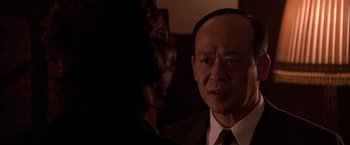 Movie still from “Black Rain” (1989), directed by Ridley Scott – An older man wearing a suit and tie looking at a woman; Close Up shot, Over the shoulder angle