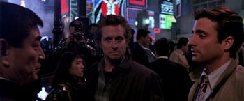 Movie still from “Black Rain” (1989), directed by Ridley Scott – A person wearing a jacket near a crowd of onlookers; Close Up shot, Low angle