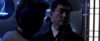 Movie still from “Black Rain” (1989), directed by Ridley Scott – A person wearing a suit and tie; Close Up shot, Over the shoulder angle