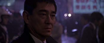 Movie still from “Black Rain” (1989), directed by Ridley Scott – A person wearing a suit and tie; Close Up shot, Over the shoulder angle