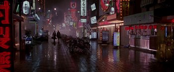 Movie still from “Black Rain” (1989), directed by Ridley Scott – People walking down a street at night in the rain; Extreme Wide shot, High angle