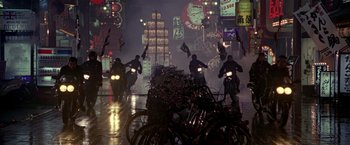 Movie still from “Black Rain” (1989), directed by Ridley Scott – A group of people riding motorcycles down a street at night; Extreme Wide shot, High angle