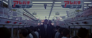 Movie still from “Black Rain” (1989), directed by Ridley Scott – A group of people walking down a crowded train platform; Wide shot, Low angle