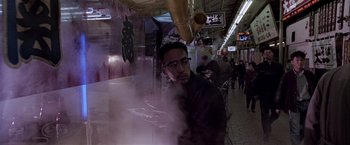 Movie still from “Black Rain” (1989), directed by Ridley Scott – A man standing next to a table in a restaurant; Medium shot, Low angle