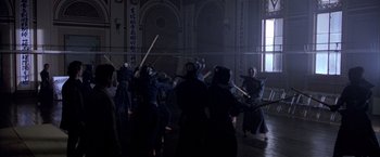 Movie still from “Black Rain” (1989), directed by Ridley Scott – A group of people are practicing martial arts in a dark room; Wide shot, High angle