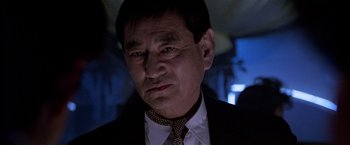 Movie still from “Black Rain” (1989), directed by Ridley Scott – A person wearing a suit and tie; Close Up shot, Low angle