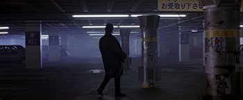 Movie still from “Black Rain” (1989), directed by Ridley Scott – A person walking in a dark area near a pillar; Wide shot, Low angle