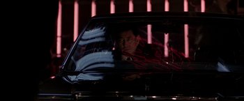 Movie still from “Black Rain” (1989), directed by Ridley Scott – A man sitting in the back seat of a black car; Medium shot, Low angle