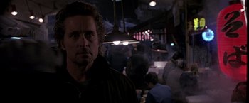 Movie still from “Black Rain” (1989), directed by Ridley Scott – A man standing in front of a group of people in a room; Close Up shot, Low angle