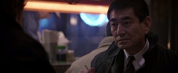 Movie still from “Black Rain” (1989), directed by Ridley Scott – An older man sitting in front of a table; Close Up shot, Over the shoulder angle