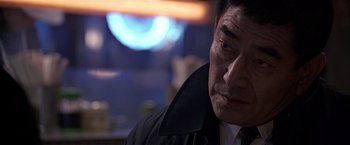 Movie still from “Black Rain” (1989), directed by Ridley Scott – A person wearing a suit and tie; Close Up shot, Over the shoulder angle