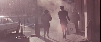 Movie still from “Black Rain” (1989), directed by Ridley Scott – Two people walking down a street with smoke coming from them; Wide shot, Low angle