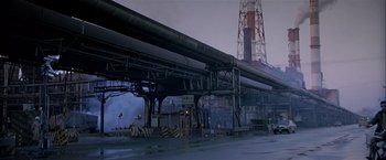 Movie still from “Black Rain” (1989), directed by Ridley Scott – An industrial area with pipes and a tower in the background; Extreme Wide shot, Low angle