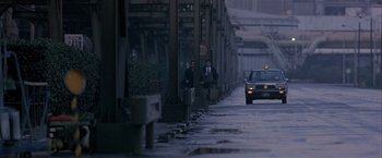 Movie still from “Black Rain” (1989), directed by Ridley Scott – Two men are walking down the sidewalk in the rain; Extreme Wide shot, Low angle