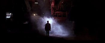 Movie still from “Black Rain” (1989), directed by Ridley Scott – A man standing in the middle of a dark room; Extreme Wide shot, High angle