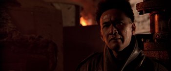 Movie still from “Black Rain” (1989), directed by Ridley Scott – A person with a fire in the background; Close Up shot, Over the shoulder angle