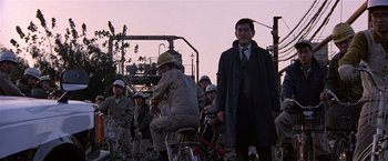 Movie still from “Black Rain” (1989), directed by Ridley Scott – A group of people riding bikes in front of an electrical tower; Wide shot, Low angle