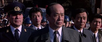 Movie still from “Black Rain” (1989), directed by Ridley Scott – A group of men standing next to each other in front of a building; Close Up shot, Low angle