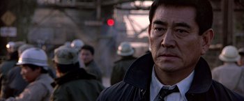 Movie still from “Black Rain” (1989), directed by Ridley Scott – A person wearing a suit and tie; Close Up shot, Over the shoulder angle